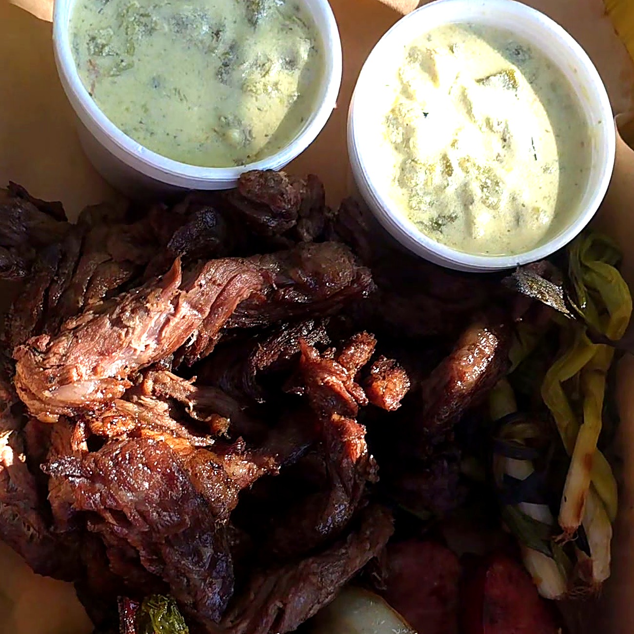 Charola de Pecos Grill con carne asada, salchicha, cebollitas y dos dips de chile con queso