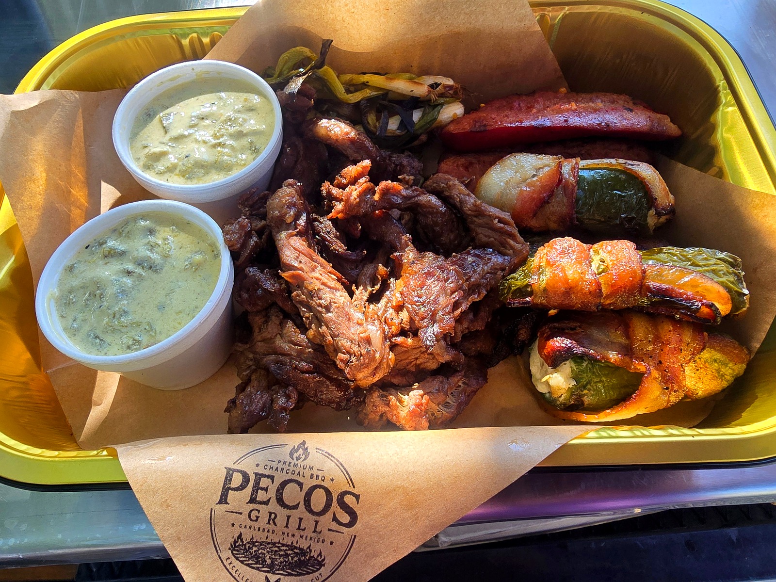 Charola de Pecos Grill con carne asada, salchichas, momias y dips de chile verde
