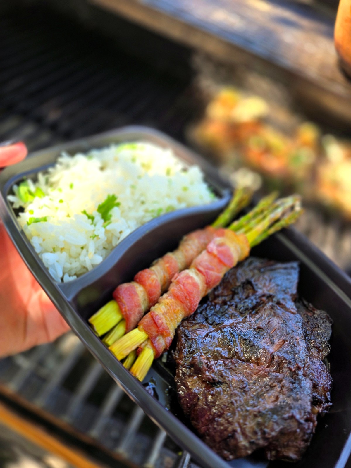 Charola de meal prep de Pecos Grill sobre la parrilla con carne, arroz y espárragos con tocino